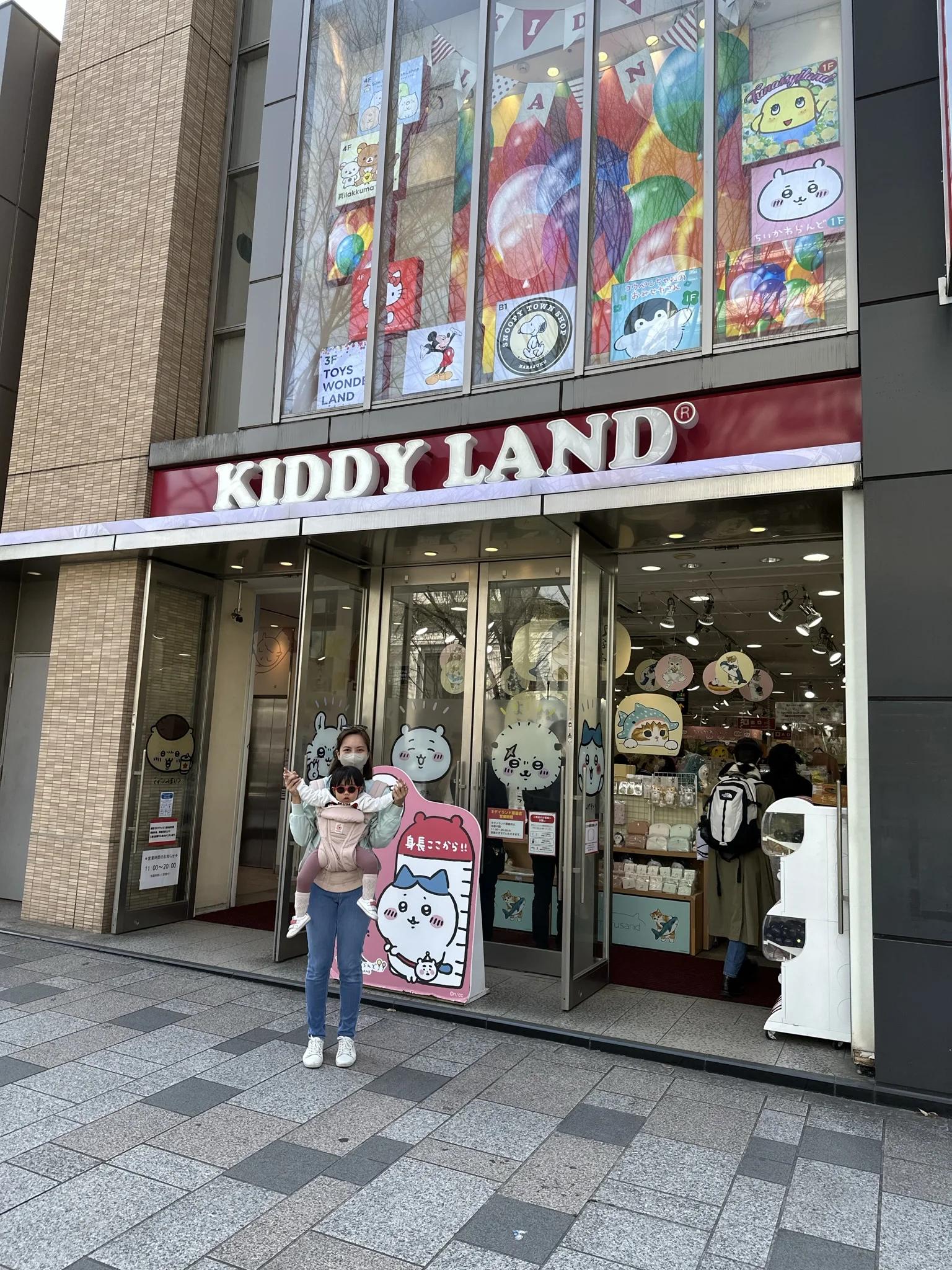 toddler in baby carrier, mum babywearing in tokyo in front of toy store