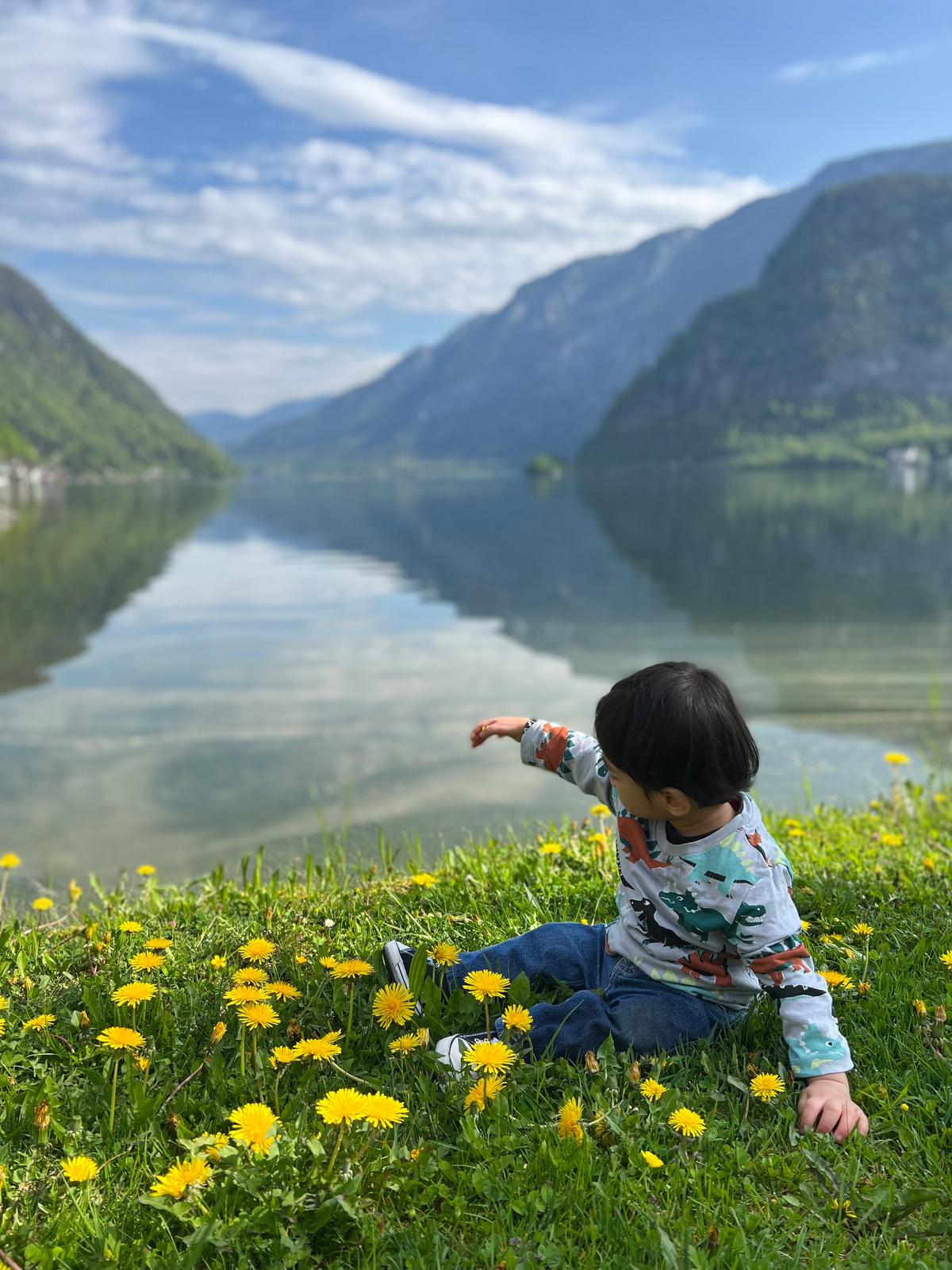 Boy toddler playing with flowers by the lake in Hallstat